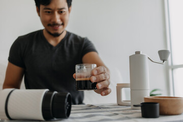 Asian man make and drink his own french press coffee.
