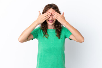 Young woman with curly hair isolated on white background covering eyes by hands and smiling