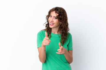 Young woman with curly hair isolated on white background pointing to the front and smiling