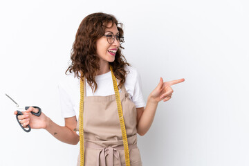 Young caucasian seamstress woman isolated on white background pointing finger to the side and presenting a product