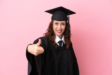 Young university graduate woman isolated on pink background with thumbs up because something good has happened
