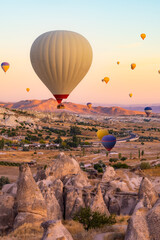 Hot air balloons flying over ancient beautiful valley during sunset in Cappadocia, Turkey