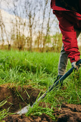  Farming, gardening, farming and people concept - unrecognizable young woman with a shovel digs the ground in a farm on a sunny day.