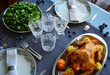 Restaurant table with crystal glasses, roast chicken and salad