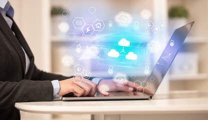 Hands working on laptop with digital icons