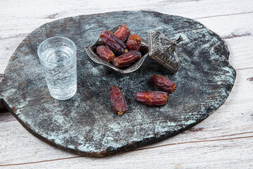 Dates or dates palm fruit (Hurma) is a healthy snack. Him Organic Medjool Ready-to-Eat Dates. Ramadan concept: Dates, zam zam water in copper jugs and glasses and on white table. - obrazy, fototapety, plakaty