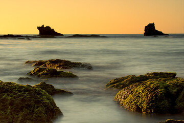 rocks lined up in silky water pointing to islets on the horizon