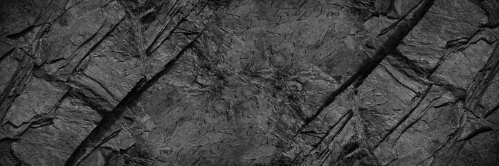 Black rock texture. Rough mountain surface with cracks. Close-up. Granite stone background with space for design. Web banner. Wide. Panoramic. Dark grey. - obrazy, fototapety, plakaty