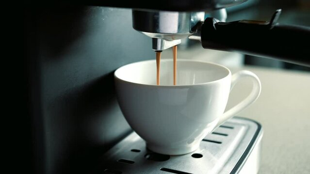 Concept Drinking roasted black coffee in the morning.Pouring coffee stream from machine in cup. Pouring coffee stream from machine in cup. Flowing fresh ground coffee. Home making hot Espresso.