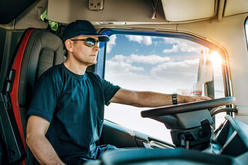 Handsome experienced male truck driver with a hat sitting and driving his truck. Professional...