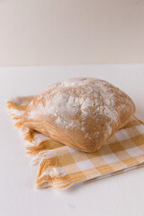 Fresh chabata bread on a yellow towel on a white background