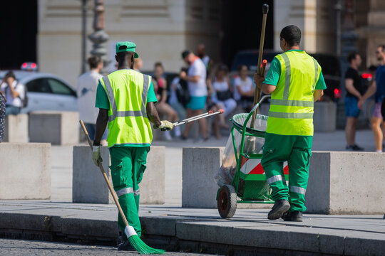 Des agents d'entretien du service public ramassant des d&eacute;chets dans la ville avec des balais et des sacs poubelles afin d'avoir un environnement propre. Concept &eacute;cologique. 