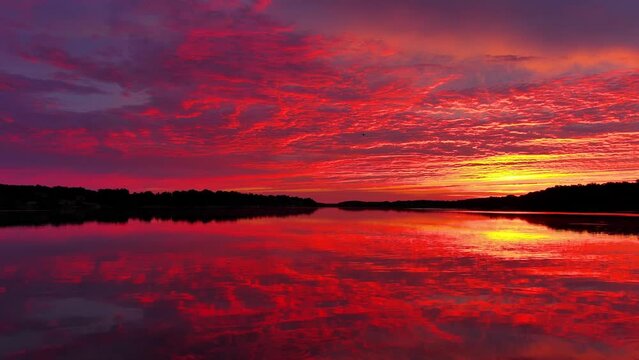 Amazing red sky mirrored in still waters at dawn, dynamic moving perspective.
