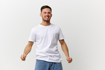 Screaming aggressive angry evil tanned handsome man in basic t-shirt clenches fists posing isolated...