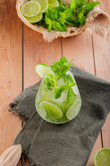 Mojito cocktail and ingredients on wooden table. Mojito with mint and lime on a green linen napkin. Summer drink concept