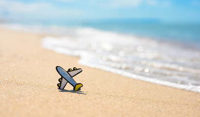 Fototapeta na wymiar A small figurine of an airplane on a sandy beach against the backdrop of sea waves. Sea travel concept, copy space.