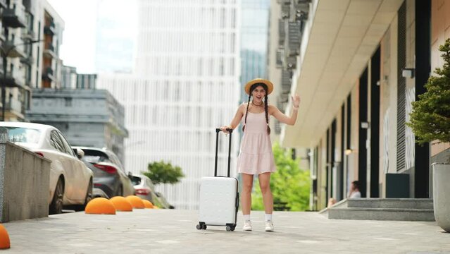 Young woman walks with a white suitcase on the street