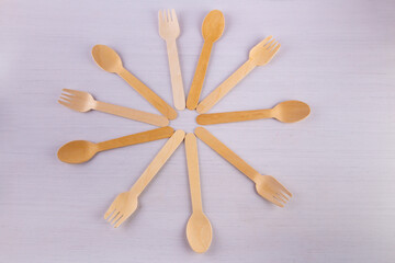Wooden eco-friendly cutlery on white background. Top view on forks, spoons lay in shape of hour hands on table