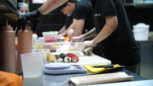 CHERKASY, UKRAINE, AUGUST 24, 2021: Sushi. Japanese Food. Cooking. Culinary. Team of sushi chefs are making different sushi rolls, at the restaurant kitchen.