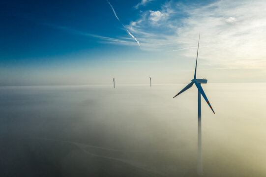 Misty sunrise and wind turbine with sun rays