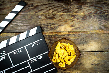 clapper board of video cinema in studio, cone corn chips in glass bowl on wooden table