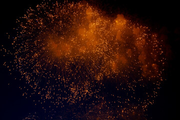 Fototapeta na wymiar Bright orange glowing fireworks with sparks flying sideways against the night sky. High quality photo