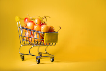 supermarket trolley with yellow cherries on a yellow background