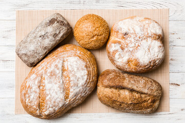 Assortment of freshly baked bread with napkin on rustic table top view. Healthy unleavened bread. French bread