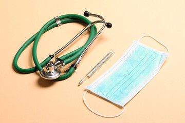 Top view of stethoscope, medical protective mask and thermometer on colorful background. Medical accessories concept