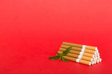 Menthol cigarettes and fresh mint leaves on colored background, Many cigarettes stacked together...