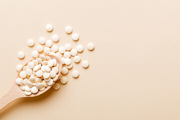 Heap of white pills on colored background. Tablets scattered on a table. Pile of red soft gelatin...