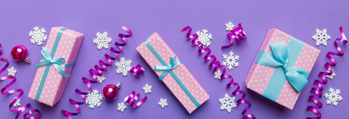 Holiday flat lay with gift boxes wrapped in colorful paper and tied decorated with confetti on colored background. Christmas, Birthday, Valentine and sale concept, top view