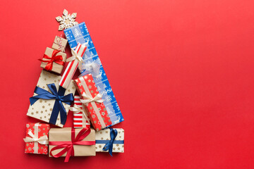 Christmas tree made of beautifuly wrapped presents on colored background, view from above. New Year gift box minimal concept with copy space