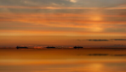 orange  gold sunset cloudy  sky at sea water reflection ship on horizon nature landscape seascape