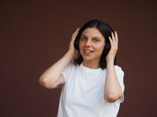 Young brunette woman wearing headphones. Young and stylish woman with dark short hair wearing a...