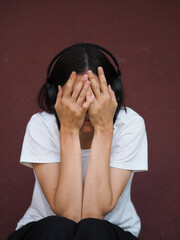 Young brunette woman wearing headphones. Young  woman with dark short hair wearing a white t-shirt...