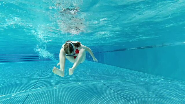 4K video of little girl having fun under water in swimming pool at summer holidays