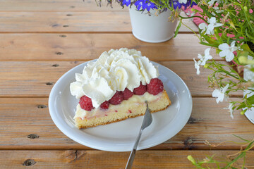 Obraz na płótnie Canvas Cake with fresh raspberries and whipped cream on a rustic wooden table, fruit dessert in summer, copy space, selected focus