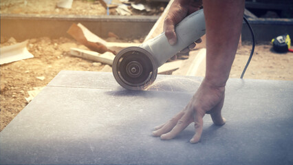 Home renovation, tiler cuts the tile with an angle grinder.
Remont domu, glazurnik docina płytkę szlifierką kątową.