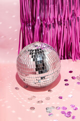 Shiny disco ball, courtain and confetti on pastel light pink background. Trendy party symbols concept. Minimalistic celebration composition.