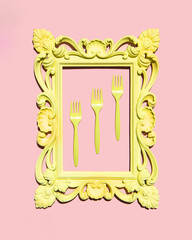 Yellow forks in frame on light pastel pink background. Creative food concept. Minimalistic food composition.