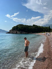 Man in shorts stands in the sea near the shore