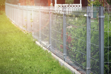 A fence made of steel panels in the garden.