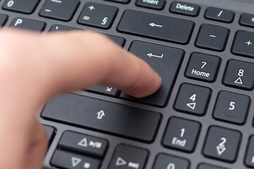 Hand pressing Enter key on notebook keyboard