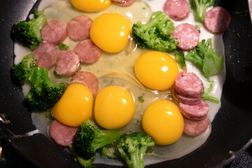 Frying eggs. Fried eggs with veggies and meat on cast iron pan. Top view of the fried eggs on...