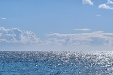 Beautiful puffy clouds in a blue sky rolling over a calm blue sea and ocean in summer. Gorgeous scenic view of the beach and blue water during the day at low tide. Idyllic and peaceful coastline