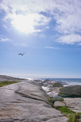 Copy space at sea with birds flying against a blue sky background and rocky coast of La Palma Canary islands Spain. Waves crashing onto beach boulders against a scenic, tropical landscape getaway