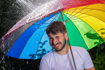 image amusante d'un jeune homme sous un parapluie. Il est sous un orage et il pleut beaucoup. Il...
