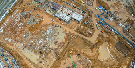 Construction of a multi-story residential buildings. A lot of construction equipment, cranes work. Construction site aerial view.