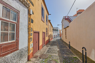 Fototapeta na wymiar Historical city street view of residential houses in small and narrow alley or road in tropical Santa Cruz, La Palma, Spain. Village view of vibrant buildings in popular tourism destinations overseas